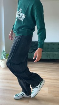 Zelena kapuca s belim tekstom, crne široke hlače i bijeli tenisice s zelenim naglasicama. Unutrašnji prostor s drvenim podom i kaučem.