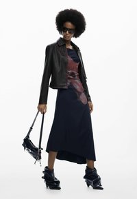 Fekete bőrkabát piros varrással, tengerészkék ruha absztrakt piros mintával, fekete minitáska és rugalmas fekete bokacsizma.