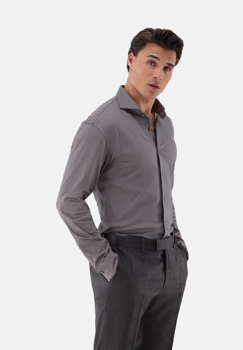 Grau kariertes Langarmhemd mit spitzem Kragen, ausgestattet mit einem Slim-Fit-Design. Kombiniert mit dunkelgrauen maßgeschneiderten Hosen.