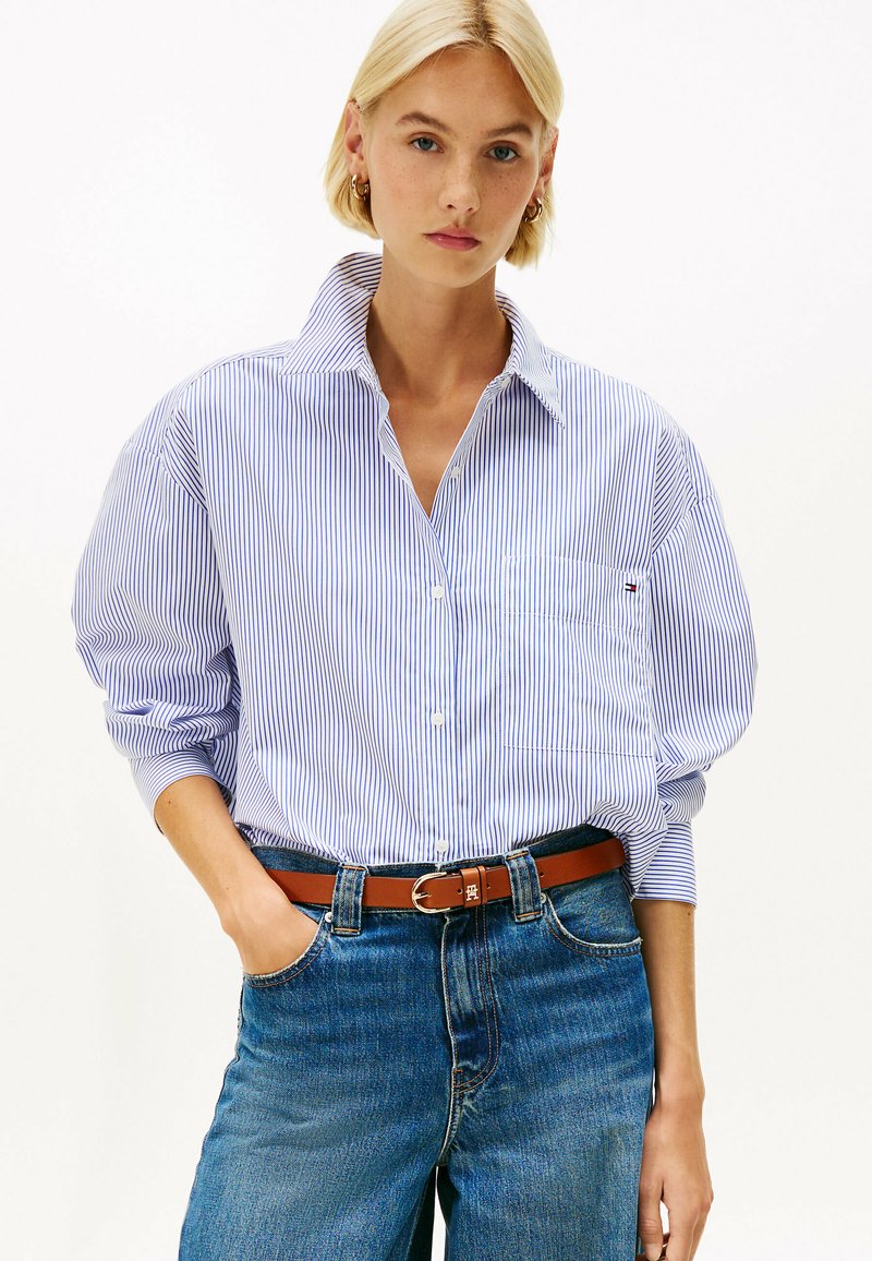 Blauw en wit gestreepte button-up shirt met een kraag, voorzien van lange mouwen en een borstzak, gecombineerd met hoge blauwe jeans en een bruine riem.