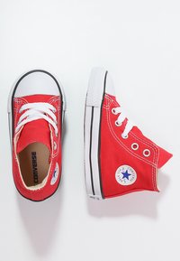Rote Leinenschuhe mit hohem Schaft und weißen Gummisohlen sowie Schnürsenkeln. Mit ikonischem rundem Logo an der Seite und schwarzem Streifendetail an der Sohle.