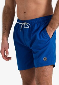 Blauwe zwembroek van lichtgewicht stof met een elastische tailleband, trekkoord, zijzakken en een klein logo op de zoom.