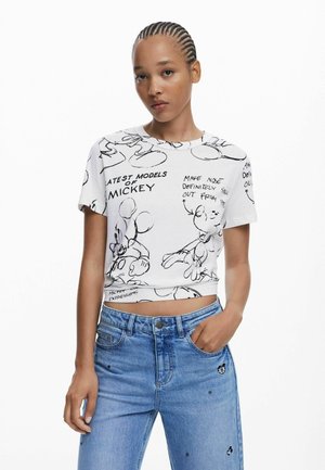 White cropped t-shirt featuring black Mickey Mouse sketches and text, short sleeves, round neckline, paired with light blue jeans.