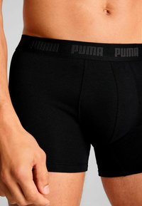 Black cotton boxer briefs featuring a wide black waistband with embossed "PUMA" logo, fitted design and smooth texture.