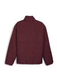 Veste matelassée bordeaux, avec un col haut, des manches longues et des coutures horizontales. Fabriquée en matériau matelassé et en quilt.