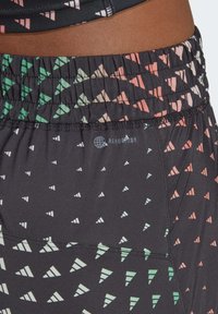 Svarta sportshorts med resår i midjan, med ett geometriskt mönster i grönt och rosa. Gjorda av AeroReady-material.