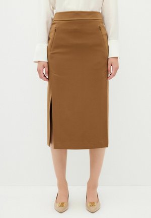 Bruine kokerrok met een zijsplit, een gladde textuur en twee voorzakken. Gepaard met beige schoenen met decoratieve accenten.