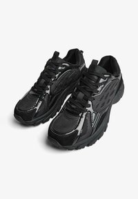 Crne atletske cipele s kombinacijom teksturirane mrežice i glatkih sintetičkih materijala, s uzdignutim uzorkom i podstavljenim potplatima.