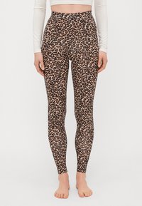 Leggings imprimés léopard avec une taille haute, un tissu extensible et une silhouette ajustée, dans une palette de couleurs beige et noir.