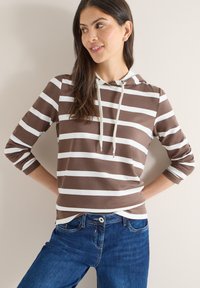 Sweat à capuche rayé marron et blanc avec cordon de serrage, manches trois-quarts, tissu doux, porté avec un jean en denim bleu.