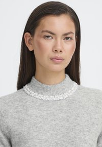 Maglione grigio a maglia con collo alto, decorato con tre file di perle bianche intorno al colletto, che aggiungono un dettaglio testurizzato.