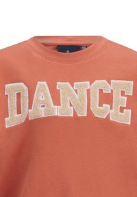 Felpa arancione realizzata in tessuto morbido con colletto a girocollo. Presenta una scritta "DANCE" in beige con lettering testurizzato in materiale gommoso e in rilievo.