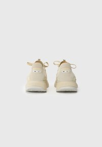 Sapatos de desporto bege com um upper em camurça texturada, design minimalista e atacadores discretos. Apresentam uma sola leve e pequenos detalhes de salto.