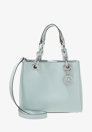 Jasnoniebieska torebka Michael Kors z podwójnymi uchwytami ozdobionymi ogniwami łańcucha i okrągłą zawieszką z logo MK, oraz długim paskiem na ramię.