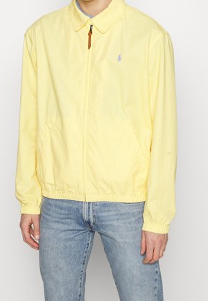 Ljusgul zip-up jacka i bomull, med spetsig krage, elastiska ärmslut och en liten logotyp på bröstet.