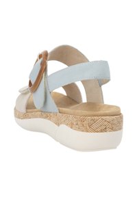 Helles blaues Sandalenmodell mit einem runden braunen Akzent, ausgestattet mit einem strukturierten Korkfußbett und einer weißen, gepolsterten Sohle für zusätzlichen Komfort.