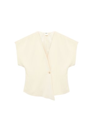 Blouse à manches courtes de couleur crème avec un col en V profond et une fermeture à bouton unique à l'avant, présentant un ourlet asymétrique et ample.
