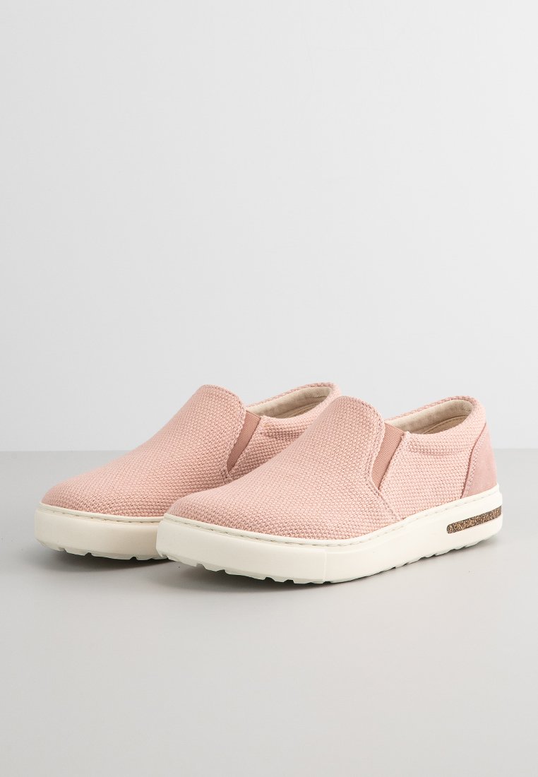 Rosa Slipper-Schuhe mit strukturiertem Obermaterial, elastischen Seitenpaneelen, einem gepolsterten Fußbett und einer weißen Gummisohle mit einem braunen Akzentstreifen.
