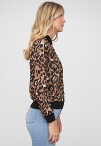 Pullover con stampa leopardata, colletto e polsini neri, realizzato in tessuto marrone chiaro morbido e dalla vestibilità comoda. I dettagli cuciti accentuano il design.