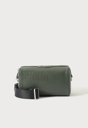 Rektangulær mørkegrøn crossbody taske med præget mønster, sølv lynlås og justerbar sort stofstrop mod en ensfarvet hvid baggrund.