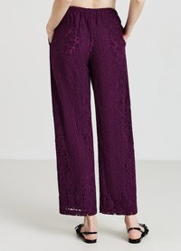 Pantaloni larghi in pizzo di colore viola scuro, con elastico in vita e motivo floreale. Comprendono tasche laterali e una texture leggera.