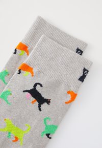 Grå stickade strumpor med färgglada kattmönster i orange, grönt och svart. Texturerad tyg med ribbade mudd.