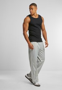 Svart ribbet tank topp, lysegrå treningsbukser med sidestriper, og svart-hvite joggesko. Enkel, tettsittende design med myk tekstur.
