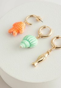 Guld hoops øreringe med tre farverige charms: en orange fisk, en grøn skal og en guldfisk, hver med unikke former og teksturer.