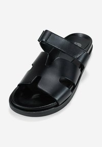 Sandalia deslizante de cuero negro con dos correas anchas. Textura suave, correa ajustable y plantilla acolchada para mayor comodidad.