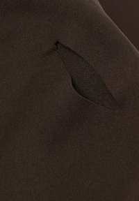 Brunt plagg med en texturerad tyg och utskärning, som visar en elegant design och slät yta.