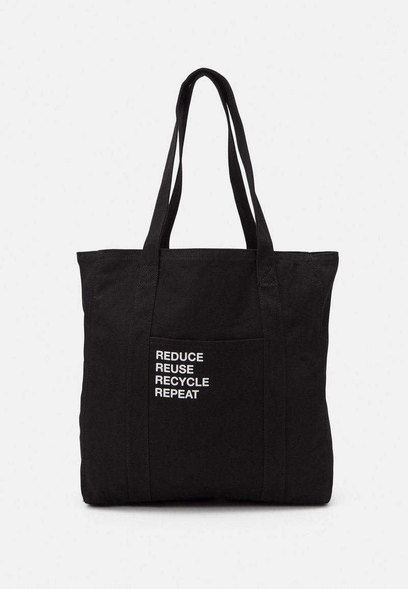 Sac cabas réutilisable noir avec longues anses et poche avant affichant un texte blanc : « RÉDUIRE RÉUTILISER RECYCLER RÉPÉTER. »
