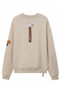 Sudadera beige con cuello redondo, hombros caídos y puños acanalados. Presenta etiquetas, una etiqueta y un acabado de tela texturizada.