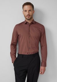 Slijtage slim-fit overhemd met lange mouwen in een rijke bruine kleur met een button-down kraag, met een gladde textuur en contrasterende donkere knopen.