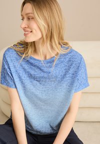 T-shirt bleu avec un motif texturé présentant des nuances variées de bleu. Design à col rond avec des manches courtes et un logo sur la poitrine.