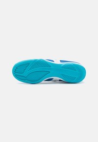 Suela de zapatilla deportiva azul y blanca con goma texturizada para agarre, presentando un patrón ondulado y áreas acanaladas para mayor estabilidad.