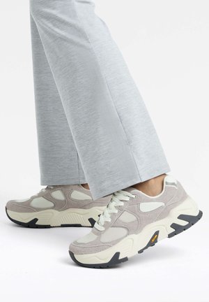 Light gray sneakers featuring a mix of suede and mesh materials, a chunky sole, and prominent black accents with laces in a matching color.