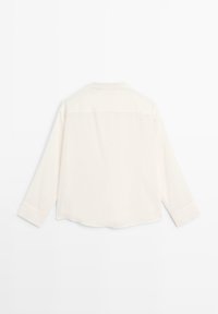 Helle Creme Langarmbluse mit weicher Textur, lässiger Passform und abgerundetem Saum. Verfügt über einen Kragen und Knopfmanschetten.