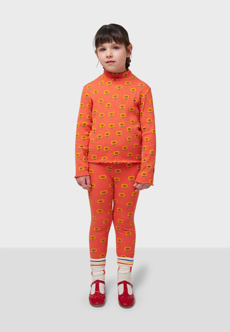 Orange long-sleeve top and leggings with yellow sunflower pattern, paired with red shoes and white socks featuring colored stripes.