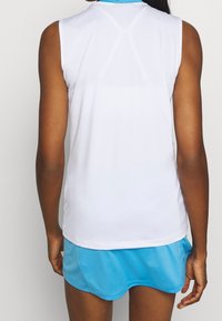 Top atletico bianco senza maniche con colletto azzurro, texture liscia e design a schiena scoperta. Abbinato a una gonna atletica azzurra.