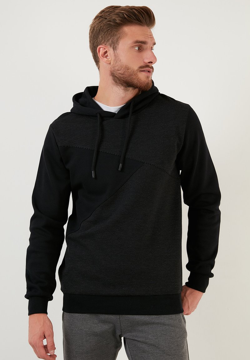 Sudadera negra con un diseño de rayas horizontales texturizadas en el pecho, cordones ajustables y un corte relajado.