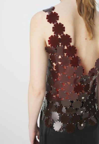 Backless top made of dark red plastic flower shapes, connected by silver hardware. Features a smooth texture and floral pattern.