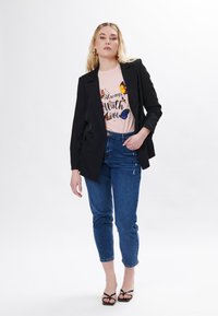 Sort skræddersyet blazer over en lyserød grafisk t-shirt med sommerfuglemotiv, parret med lyseblå denim jeans og sorte strophæle.