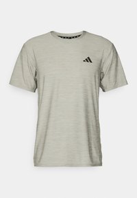 Ljust grå kortärmad atletisk T-shirt med en strukturerad yta. Har en svart logotyp på övre vänstra bröstet och ett mönstrat inre nackstycke.