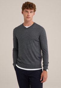 Grauer, langärmeliger V-Ausschnitt Pullover mit strukturiertem Stoff. Über einem weißen Hemd getragen, kombiniert mit dunklen Hosen. Einfaches, modernes Design.