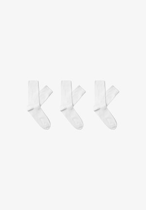 Chaussettes en coton blanches avec une texture côtelée, de longueur classique et sans motifs ni accents visibles, disposées par groupe de trois.