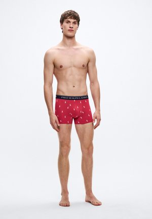 Boxer rojo con una cinturilla negra que lleva el texto "POLO RALPH LAUREN". La tela tiene una textura suave con pequeños patrones de logotipos.
