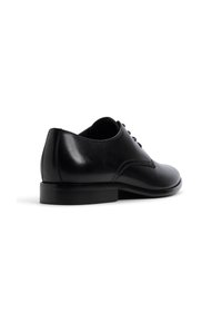 Zapato oxford de piel negra con un acabado suave, punta redondeada y cierre de cordones con cinco ojales. Presenta un tacón bajo apilado y costuras sutiles.