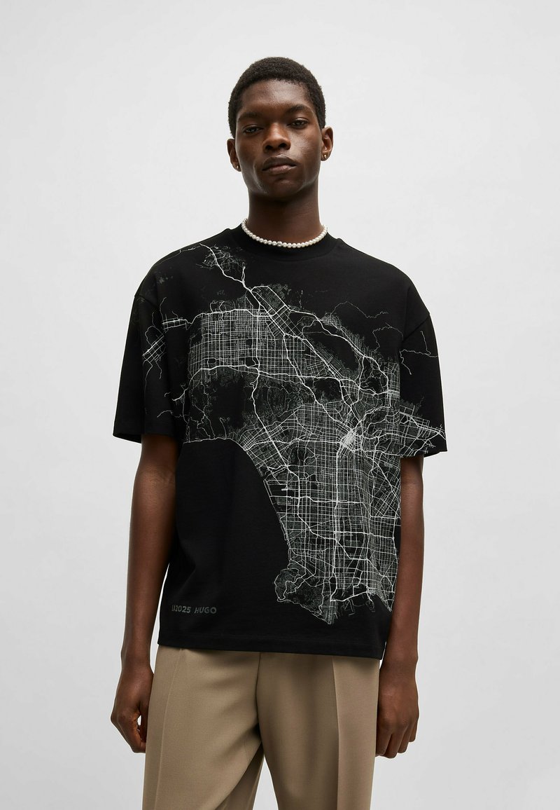 Black cotton t-shirt featuring a white map graphic across the front. Short sleeves, relaxed fit, with a small logo printed near the hem.