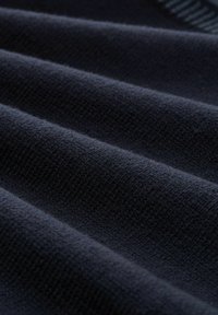 Ciemnoniebieska tkanina o teksturowej powierzchni, z delikatnymi, falującymi zagnieceniami i subtelnym, równomiernym wzorem dzianiny w całej tkaninie.