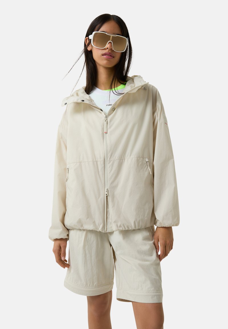 Light beige hooded jacket with front zipper and two side pockets, paired with beige shorts, featuring a casual fit and smooth texture.